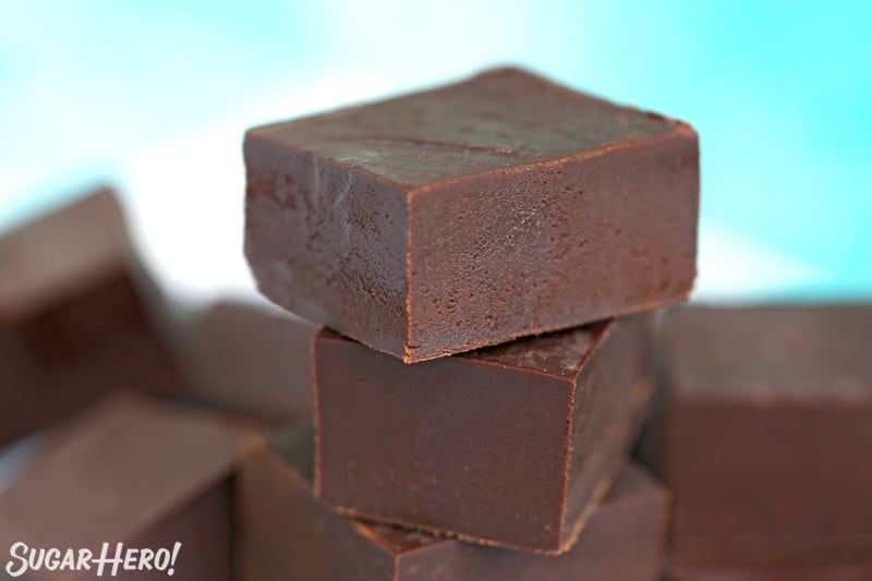 Hand lifting a piece of chocolate fudge off a stack