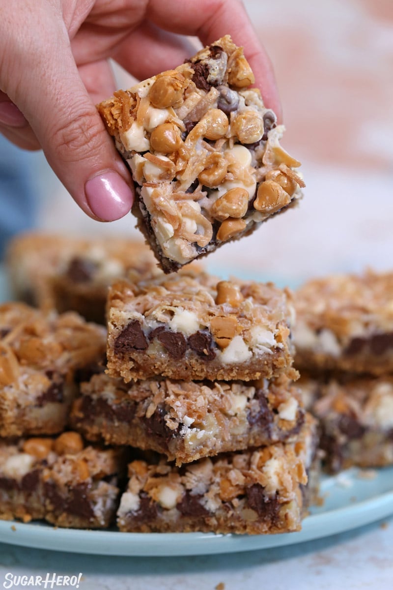 Hand taking a Seven Layer Bar from the top of a stack of bars