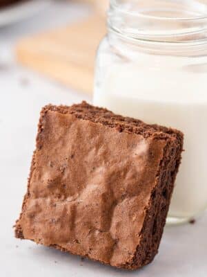 Brown Butter Brownie leaning against a mason jar of milk
