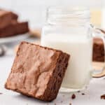 Brown Butter Brownie resting against a mason jar of milk
