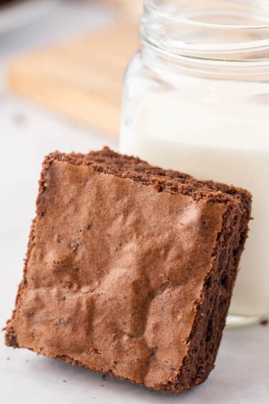 Brown Butter Brownie leaning against a mason jar of milk