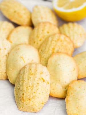 Lemon Madeleines on white parchment with a half lemon in the background