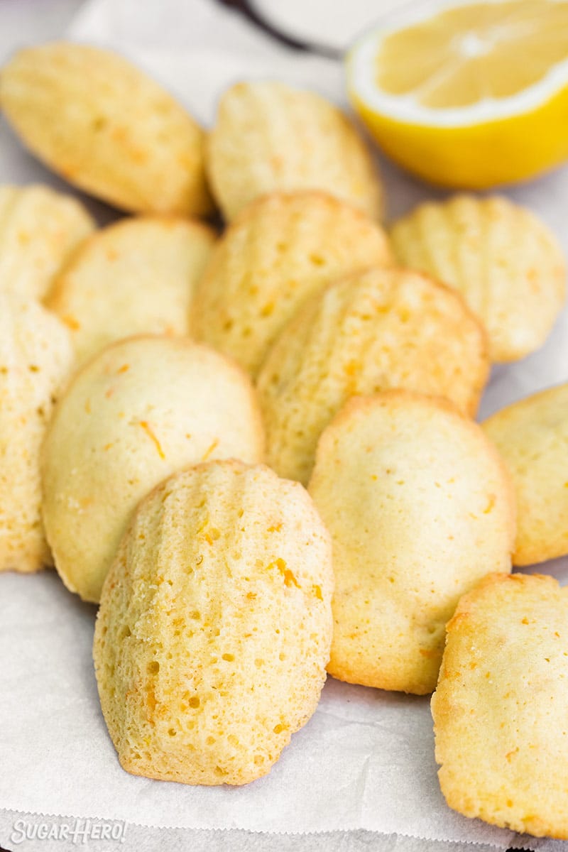 Lemon Madeleines on white parchment with a half lemon in the background