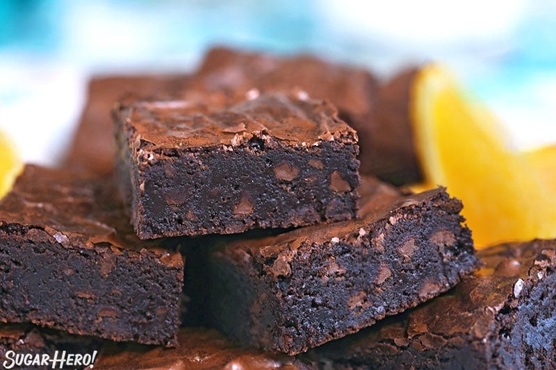 Close-up of chocolate orange brownies with orange slice in the background.