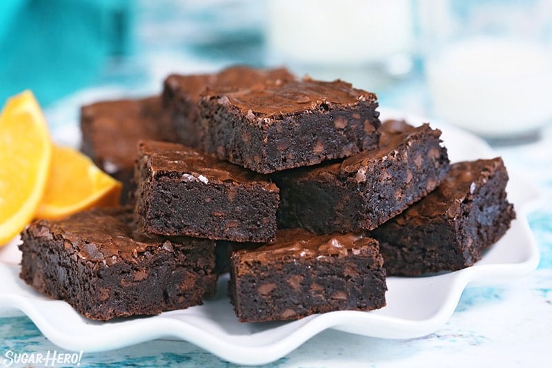 Pile of five chocolate orange brownies on a white plate.