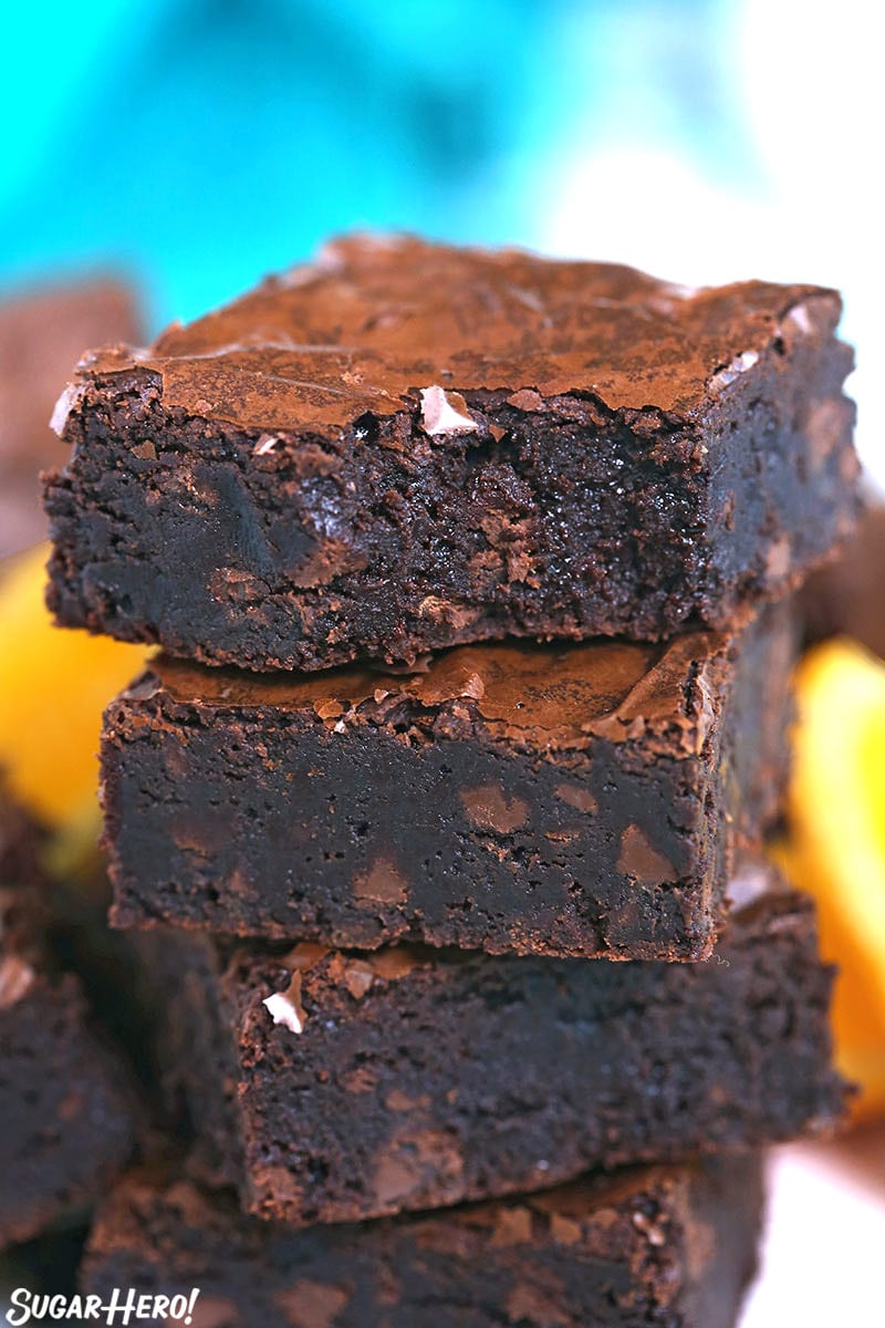 Stack of four chocolate orange brownies with a bite taken out of the top one.