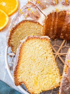 Sliced bundt cake on a wire rack with one piece leaning to the side.