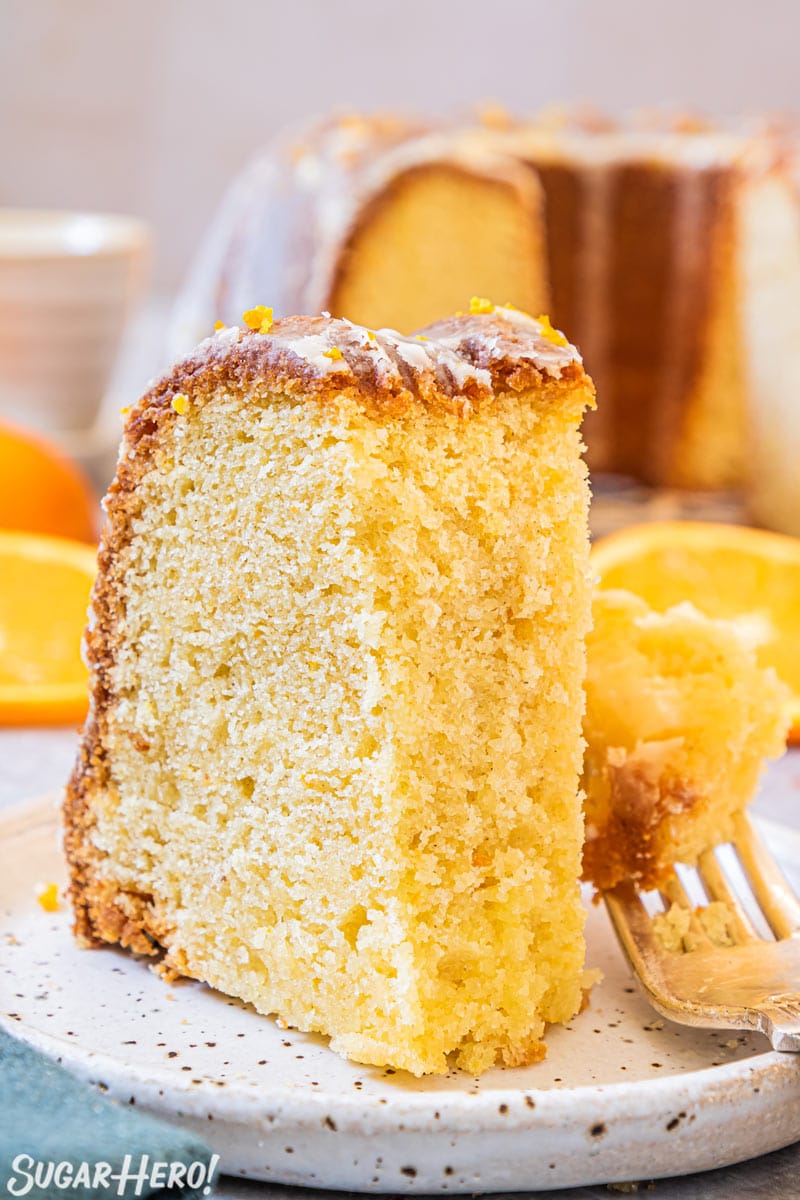 Slice of orange bundt cake on plate with a bite taken out of it.