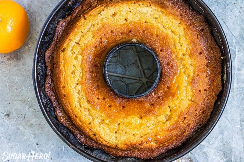 Baked bundt cake in a pan, with holes poked in top for syrup to seep in.