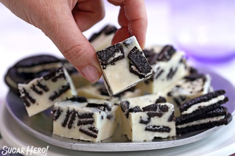 Hand picking up a piece of Oreo Fudge from a plate.