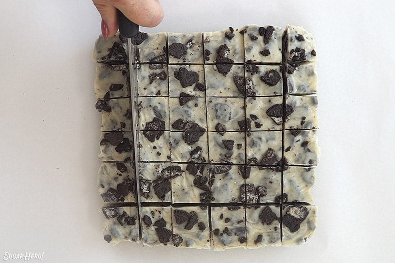 Large knife slicing a block of cookies and cream fudge