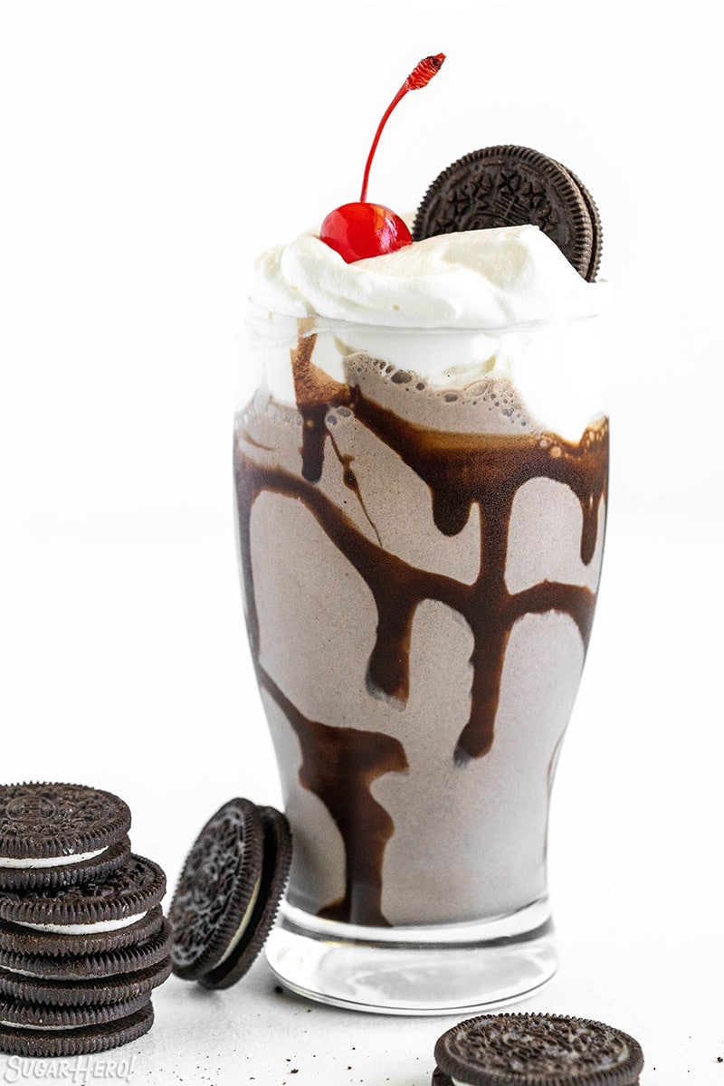 Oreo Milkshake in a glass with whipped cream, a cherry on top, and an Oreo.