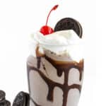 Glass filled with Oreo Milkshake and topped with whipped cream and an Oreo cookie.