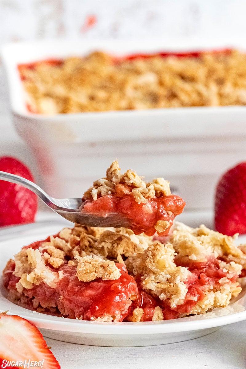 Spoon serving up a scoop of Strawberry Crisp on a white plate.