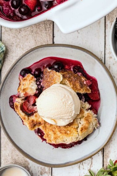 Top view of a serving of berry cobbler with a schoop of ice cream on top.
