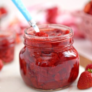 Jar of Strawberry Sauce with fresh strawberries to the side.