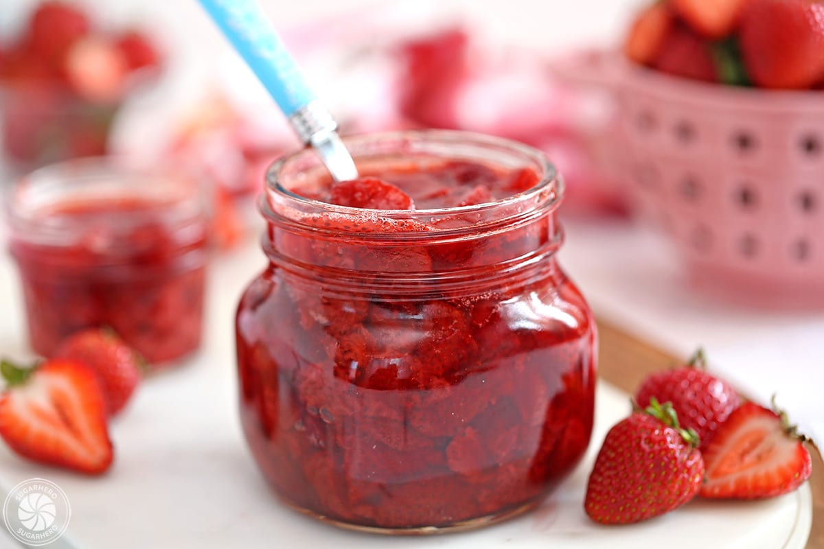 Jar of Strawberry Sauce with fresh strawberries to the side.