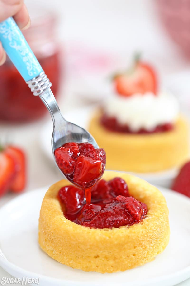 Blue spoon scooping Strawberry Sauce into an angel food cake cup.