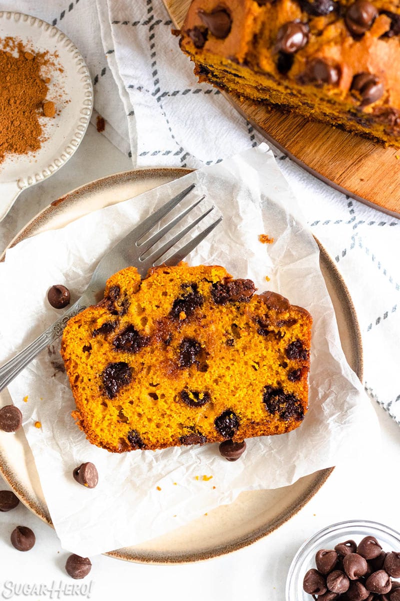 Slice of Pumpkin Chocolate Chip Bread on a piece of white parchment paper on a plate.