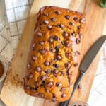 Overhead shot of a loaf of Pumpkin Chocolate Chip Bread on a wooden cutting board.