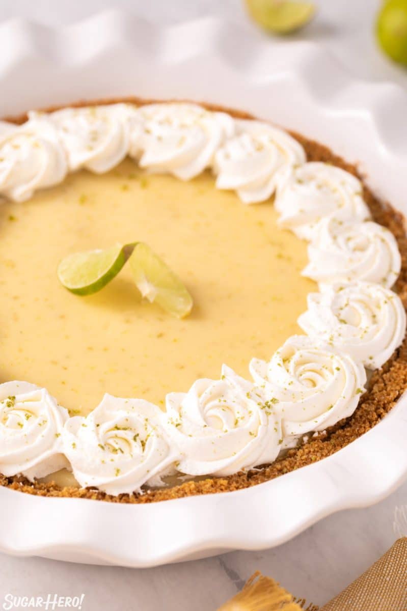 Key Lime Pie in a white pie plate with whipped cream rosettes around the edge.