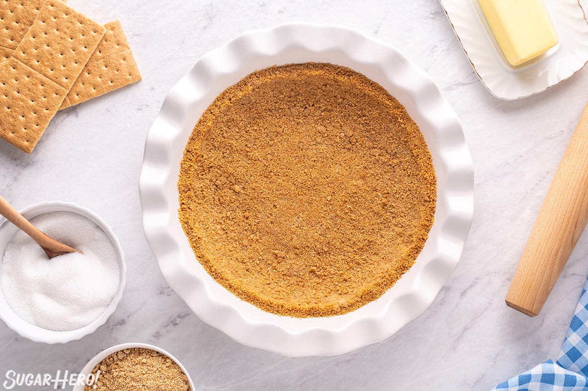 Overhead shot of graham cracker crust pressed into a white pie pan.