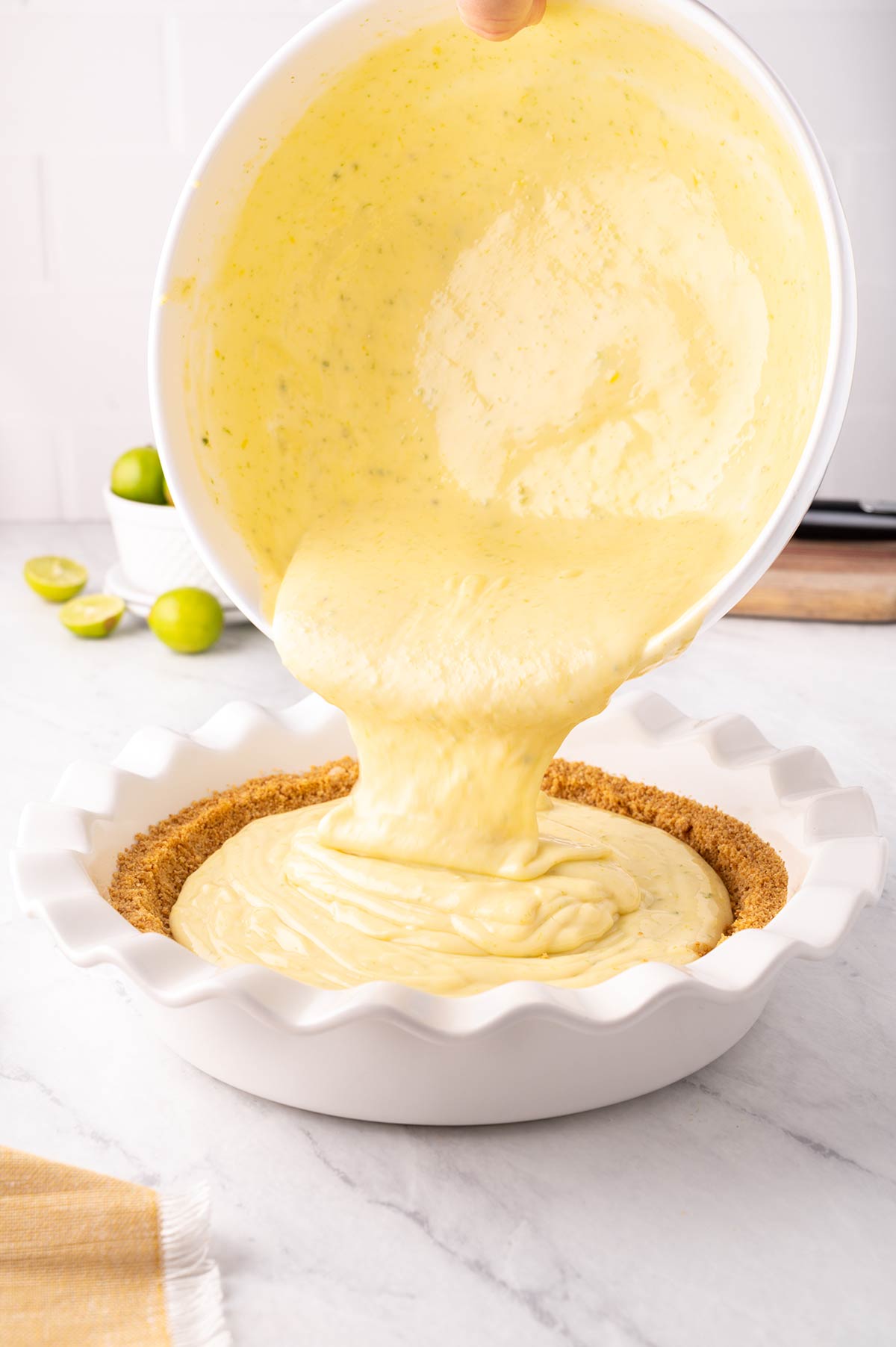 Pouring key lime filling into a graham cracker crust.