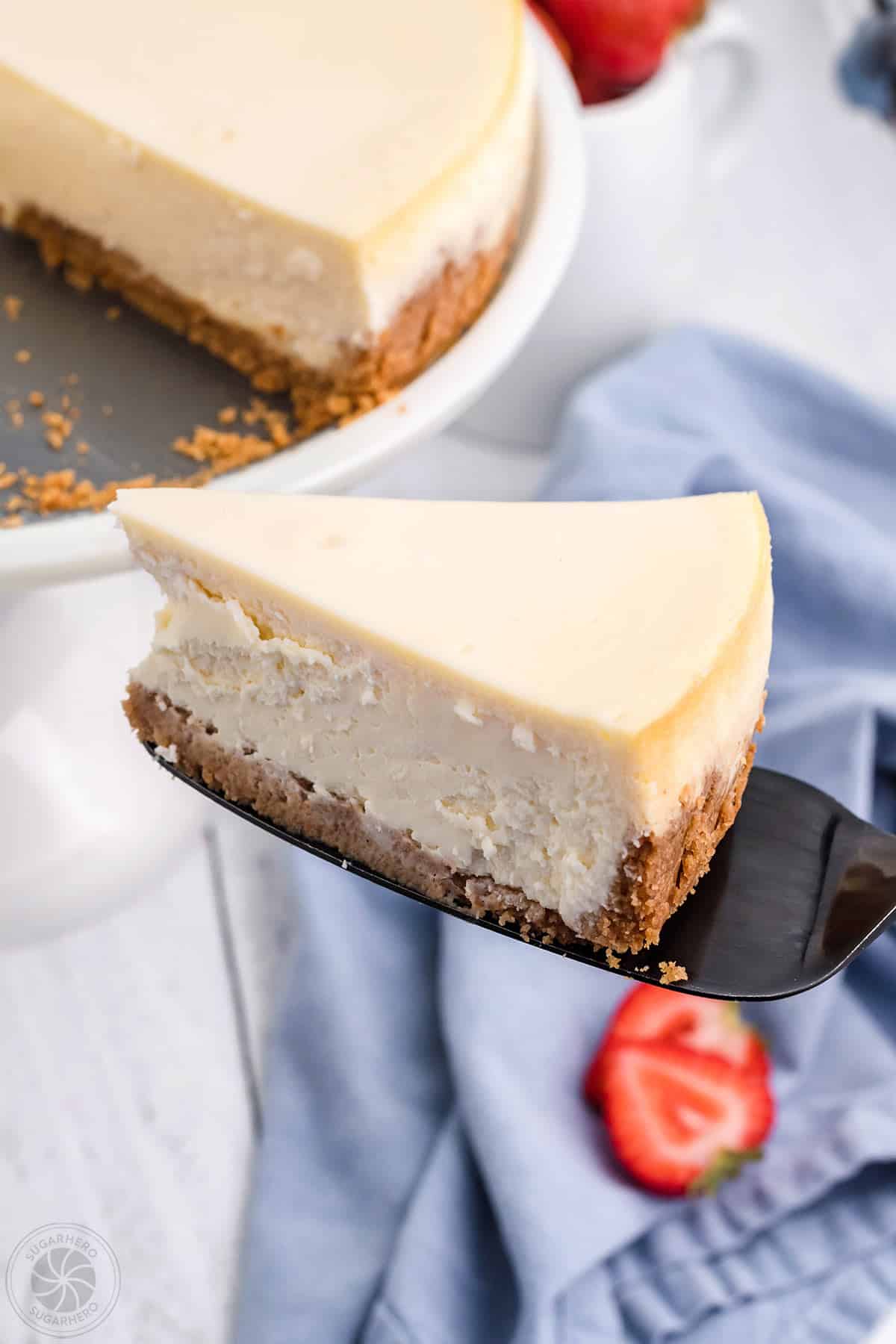 Cake server removing a single slice of New York Style Cheesecake.