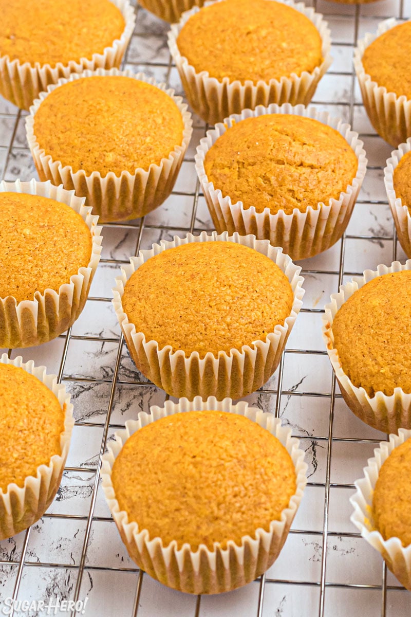 A dozen pumpkin Spice Cupcakes on a cooling rack before they are frosted.