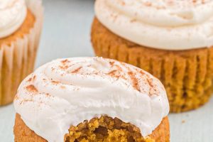 Photo of three pumpkin spice cupcakes, one with a bite missing and the words "Pumpkin Cupcakes" overlaid.
