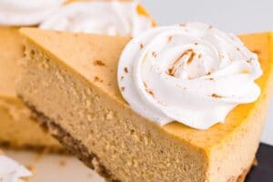 Pinterest collage showing a slice of pumpkin spice cheesecake topped with whipped cream (the rest of the cheesecake blurred out in the background).