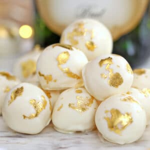 Several Champagne White Chocolate Truffles on a white marble surface.
