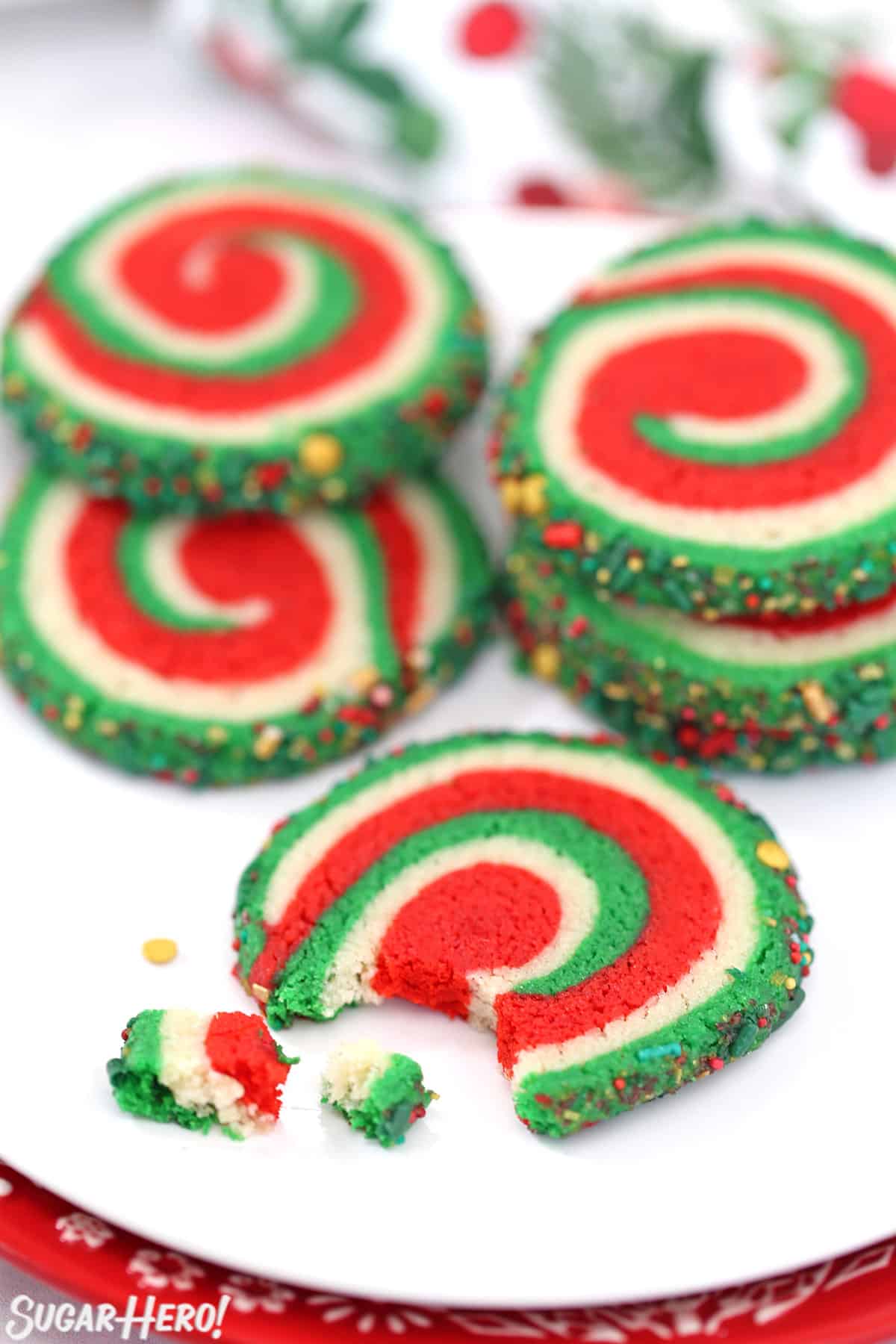 White plate with pinwheel cookies on it and a cookie with a bite taken out of it in the foreground.