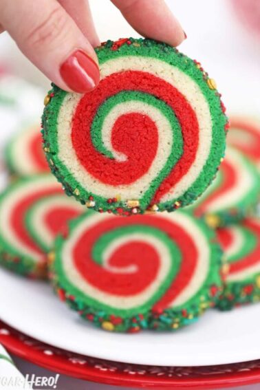 Hand holding up a red, white, and green pinwheel sugar cookie.