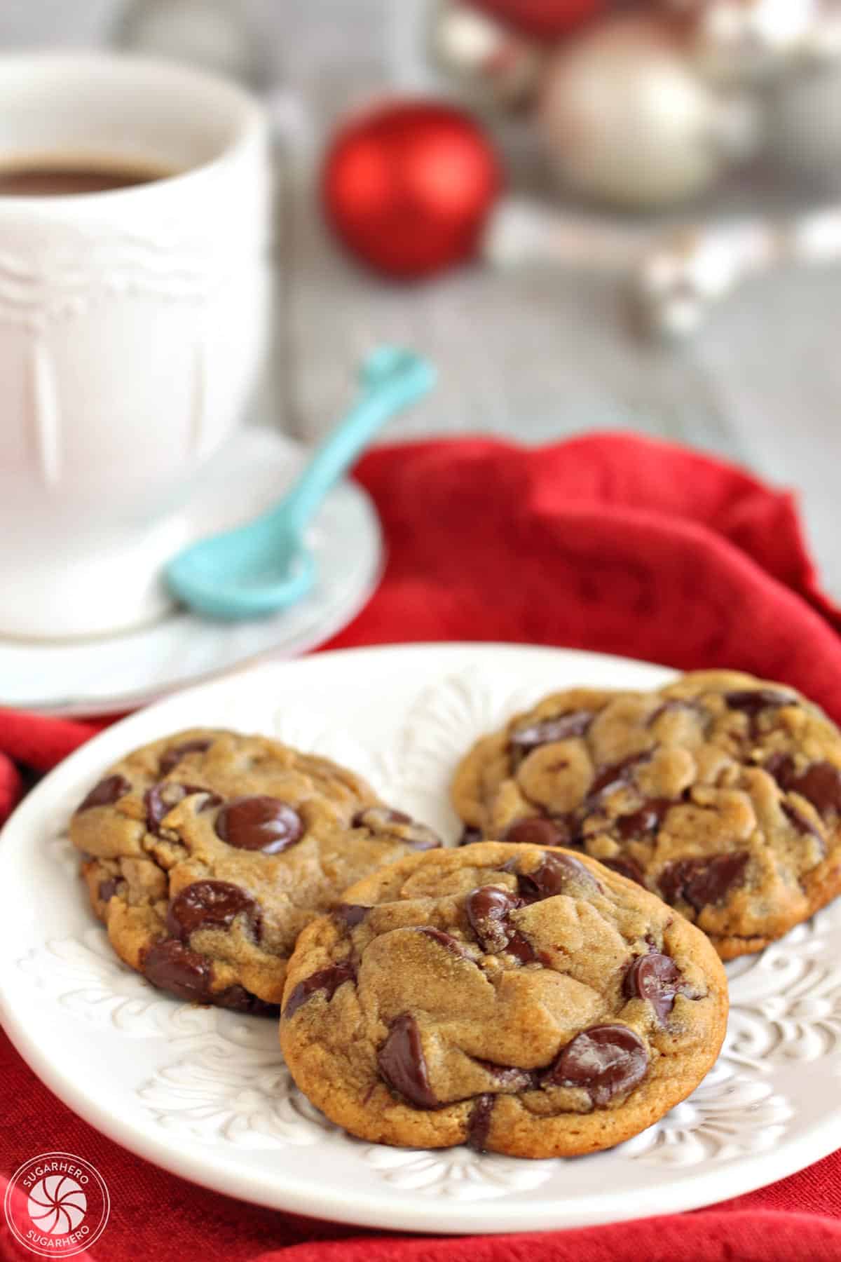 Three Gingerbread Chocolate Chip Cookies on a white plate with a red napkin in the background.