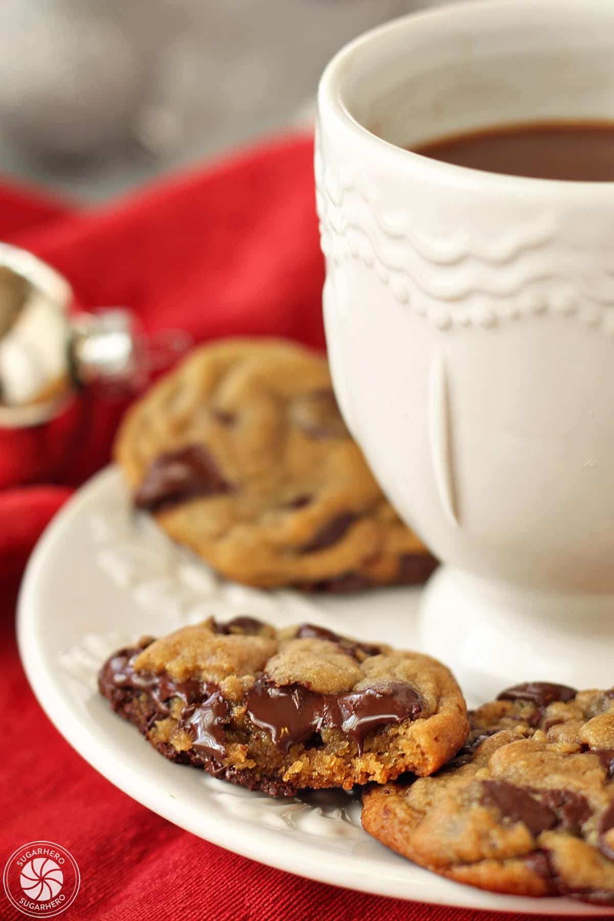 A plate of Gingerbread Chocolate Chip Cookies arranged around a mug of hot cocoa.