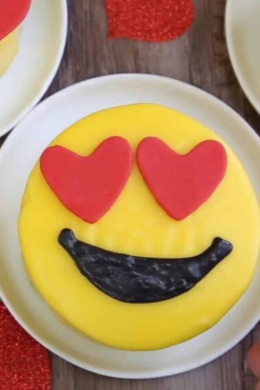 Overhead shot of a heart-eyed Emoji Cake on a wood surface.
