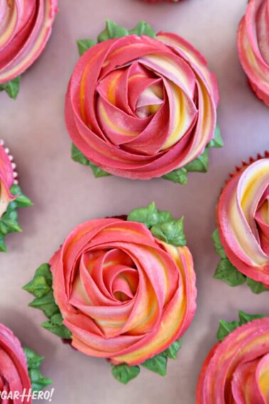 Pink and yellow swirled Rosette Cupcakes on a gray surface.
