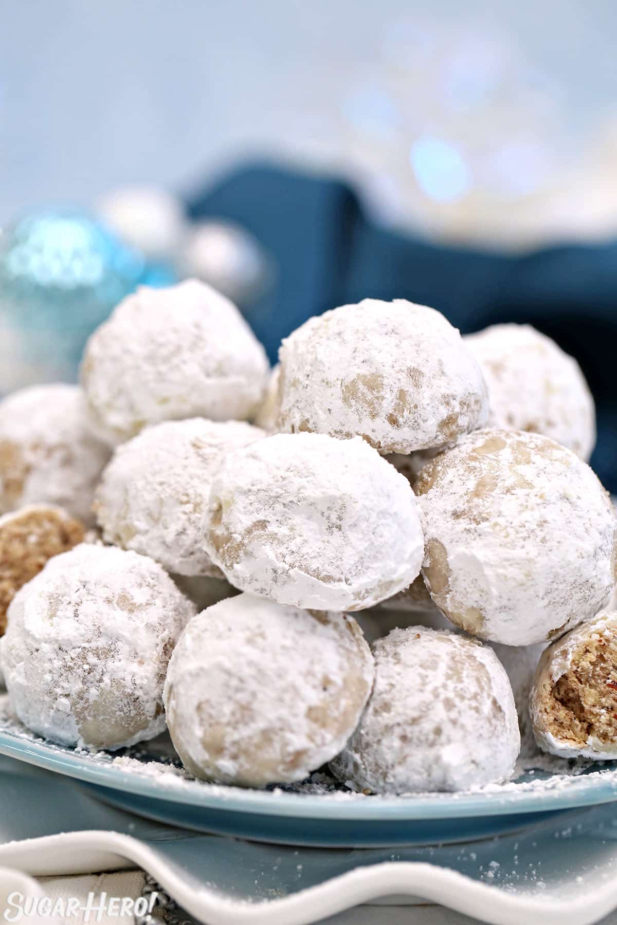 Snowball cookies on a light blue plate with a blue napkin in the background.