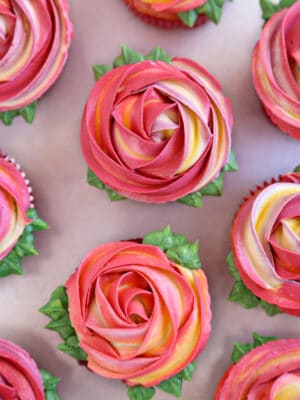 Pink and yellow swirled Rosette Cupcakes on a gray surface.