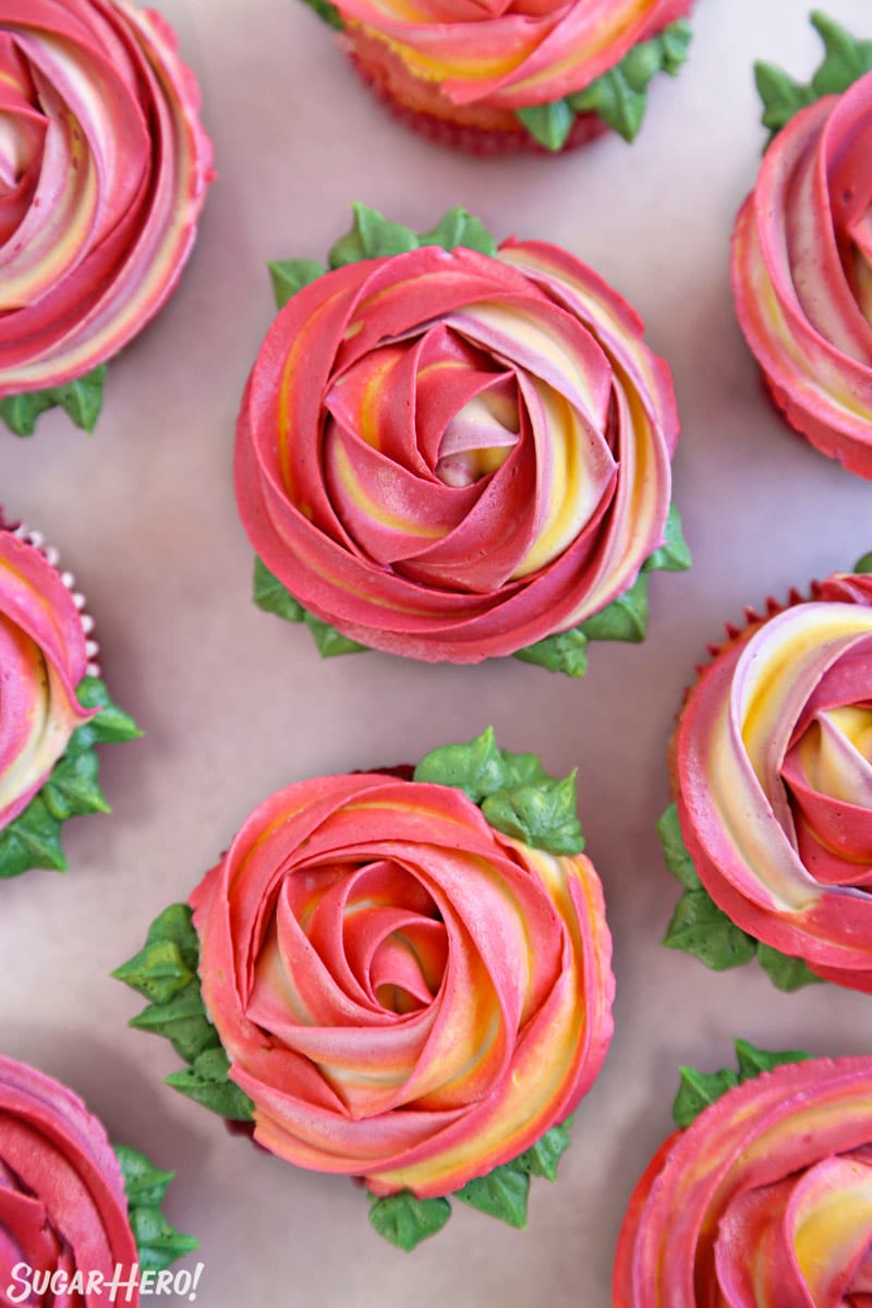 Pink and yellow swirled Rosette Cupcakes on a gray surface.