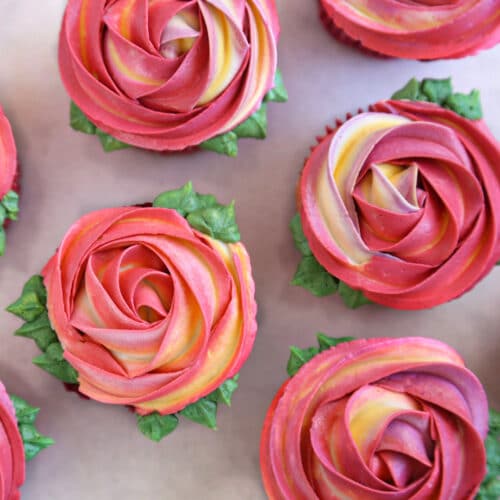Overhead shot of pink and yellow Rosette Cupcakes with piped leaves around the edges.