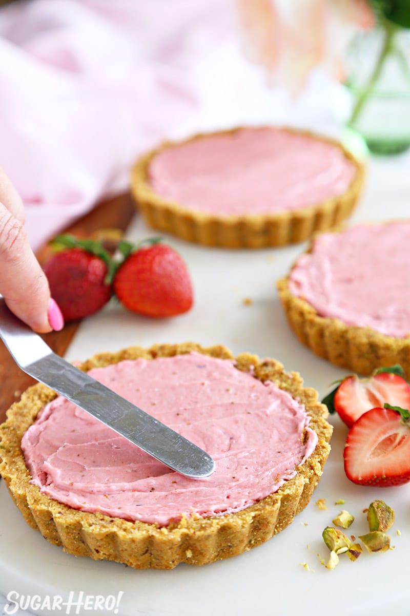Spreading strawberry-rose filling in miniature tart shells.