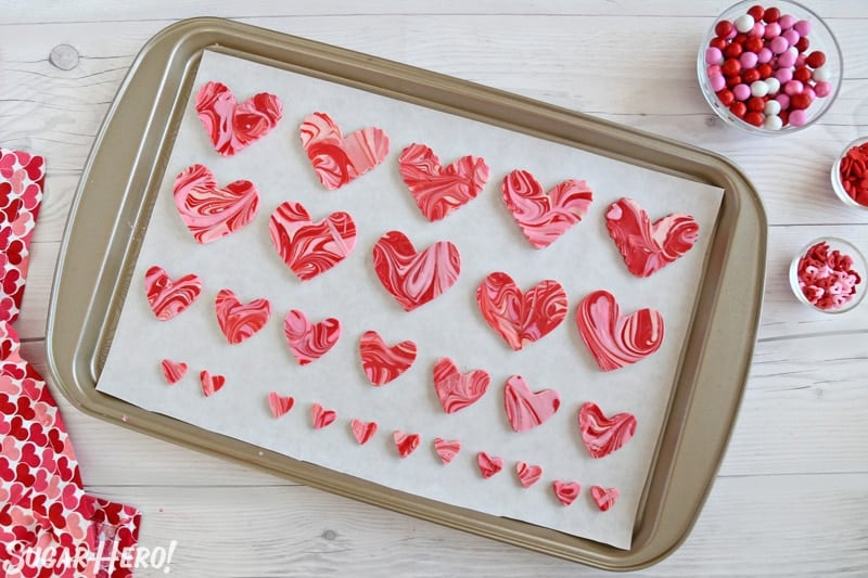 Baking sheet covered with parchment, with swirled chocolate hearts arranged on it.