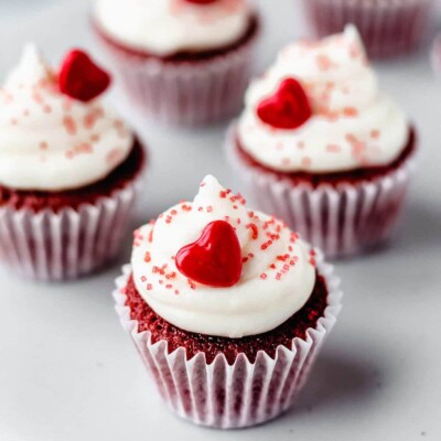 Mini Red Velvet Cupcakes on a white surface, with a red candy heart on top.