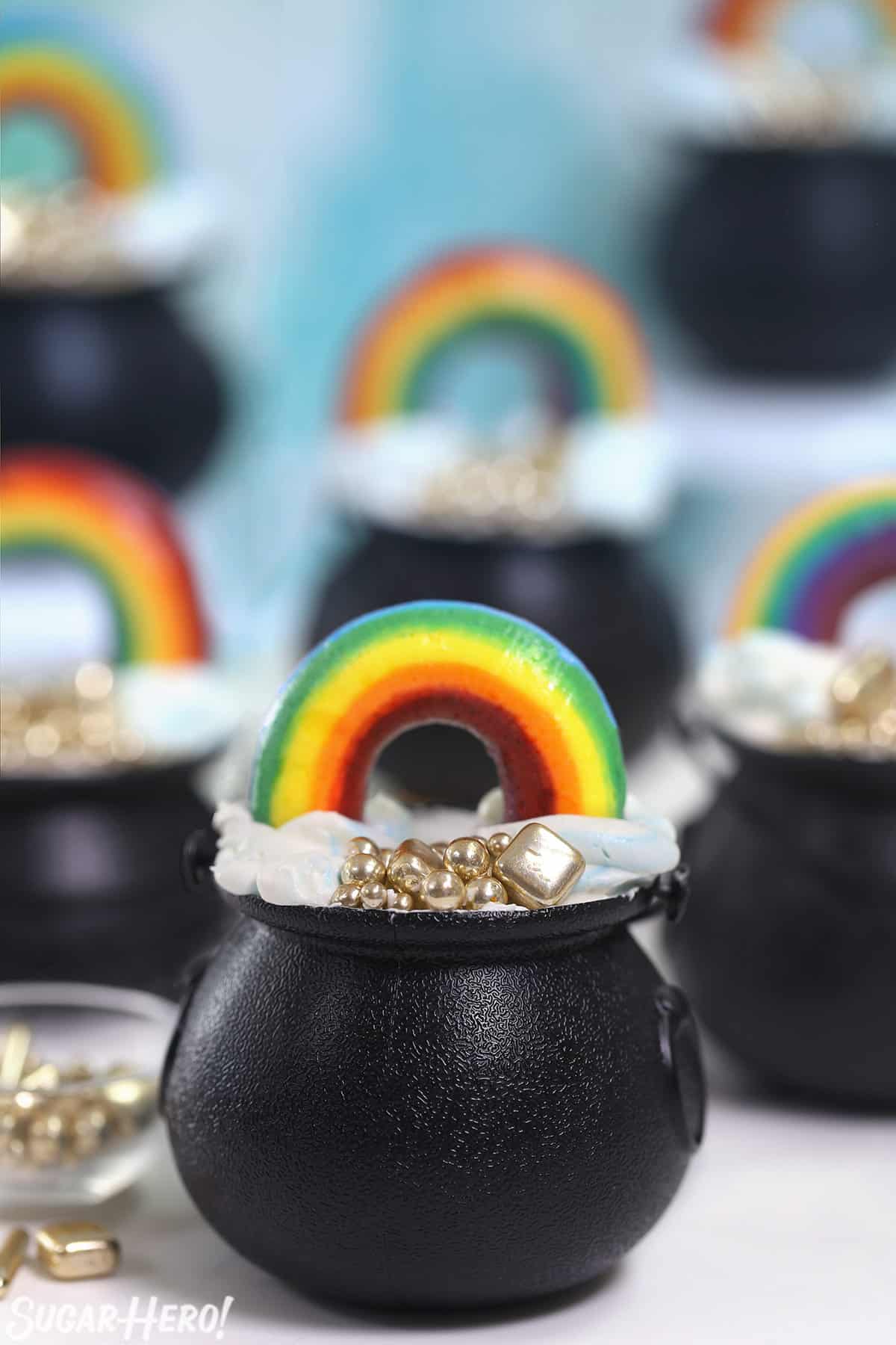 Group of Pot of Gold Cupcakes on a white surface with a blue cloud background.