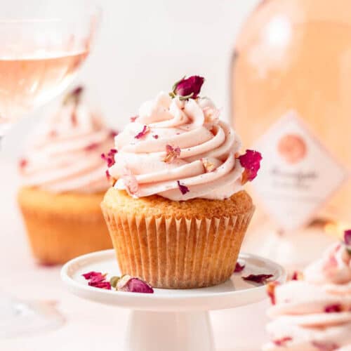 Rosé Cupcake on a small white cupcake stand, with a bottle and glass of Rosé in the background.
