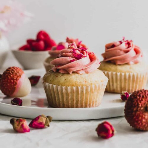 Single Rose Lychee Raspberry Cupcake on a white cake plate and cut to show inside heart-shape.