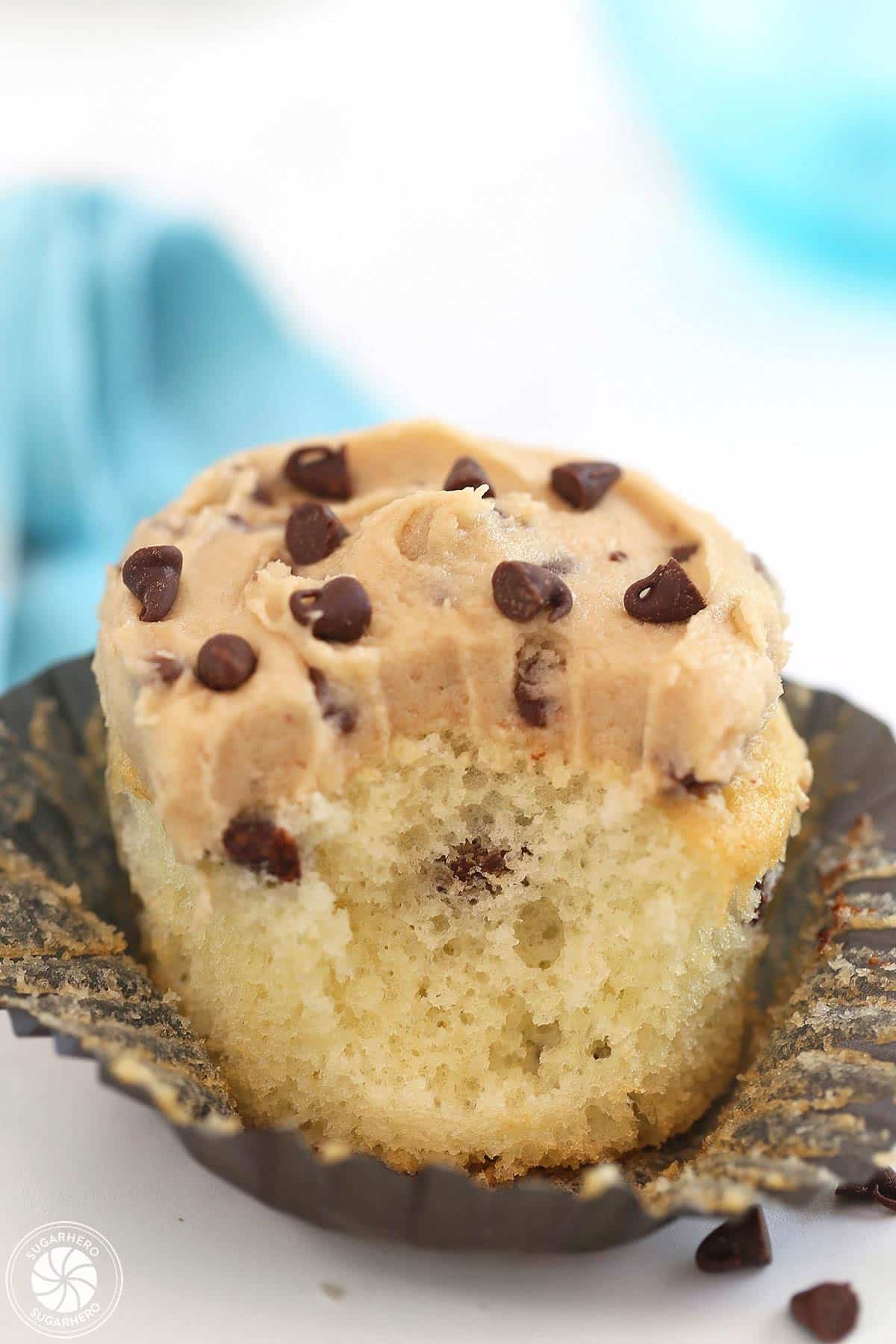 Close-up of a cupcake frosted with Cookie Dough Frosting with a big bite taken out of it.