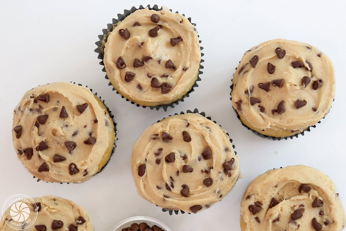 Overhead shot of six cupcakes frosted with Cookie Dough Frosting and mini chocolate chips scattered on top.